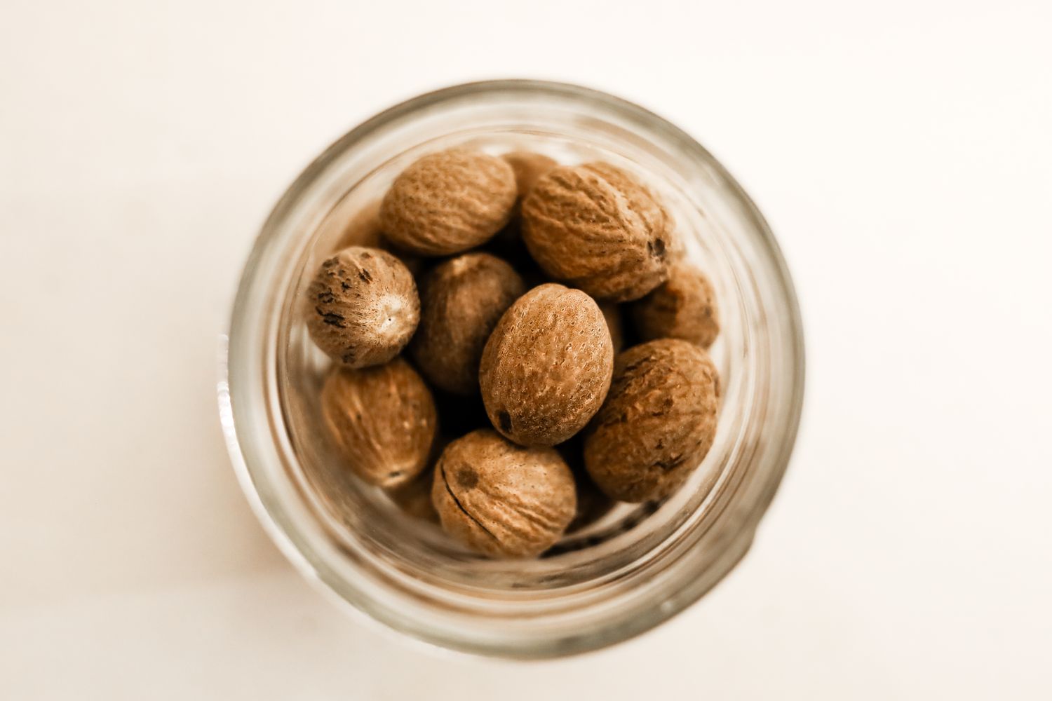 Whole nutmegs inside a glass jar viewed from above