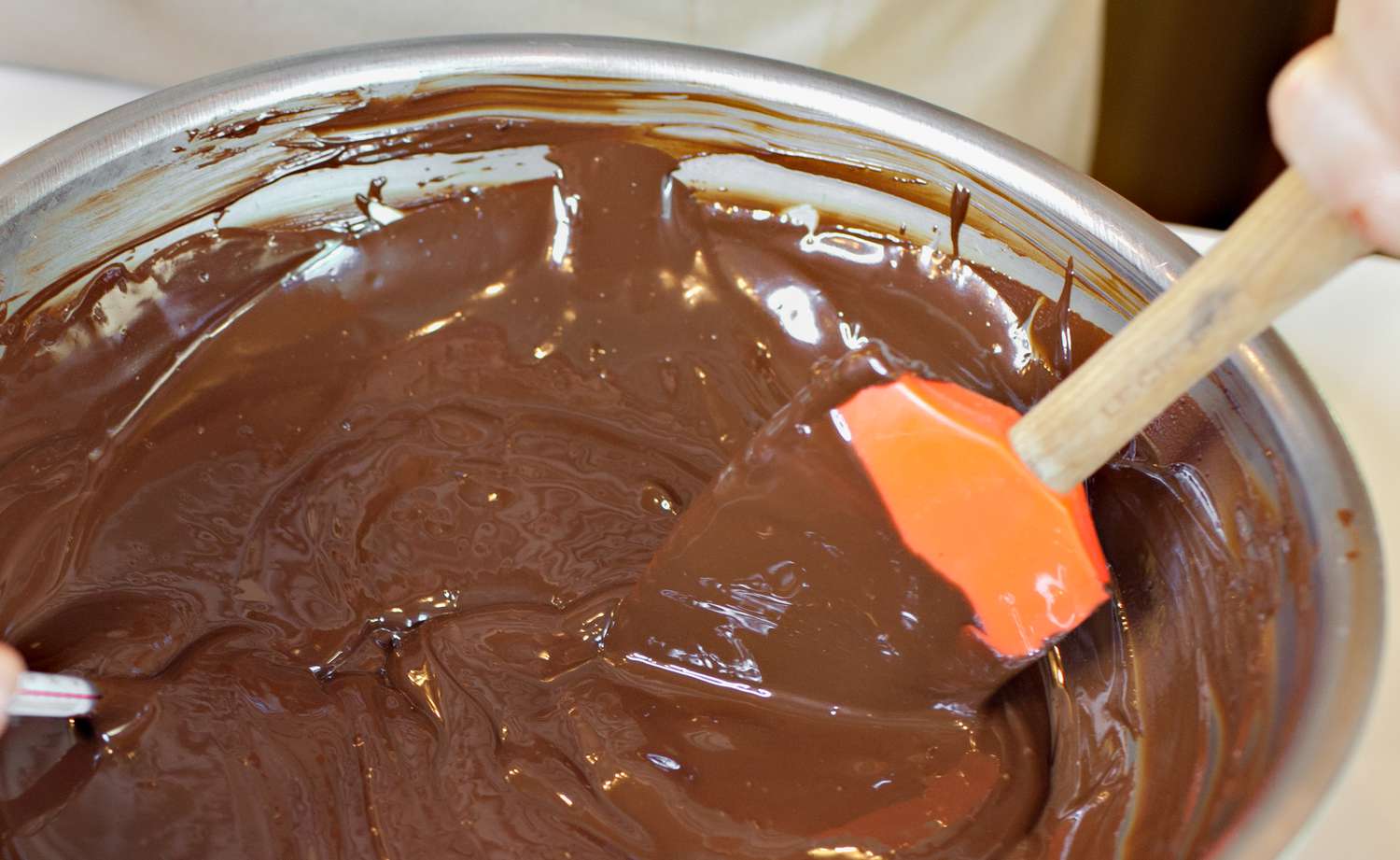 Bowl of Melted Chocolate Mixed Using a Rubber Spatula and in the Corner, a Thermometer Used to Measure Temperature for How to Temper Chocolate