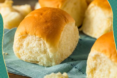 Photo of dinner rolls on a tea towel with fun line illustrations on the edges of the photo 