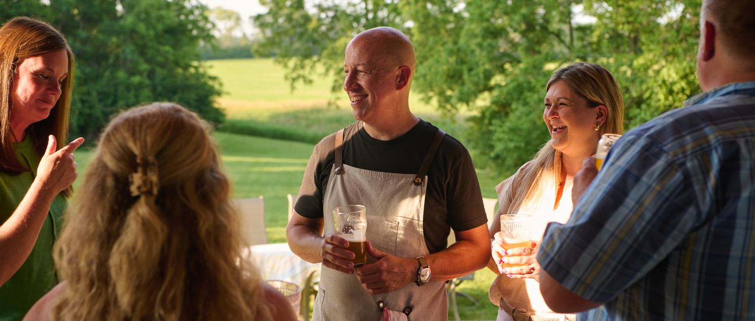 People gathered outdoors, talking and holding drinks