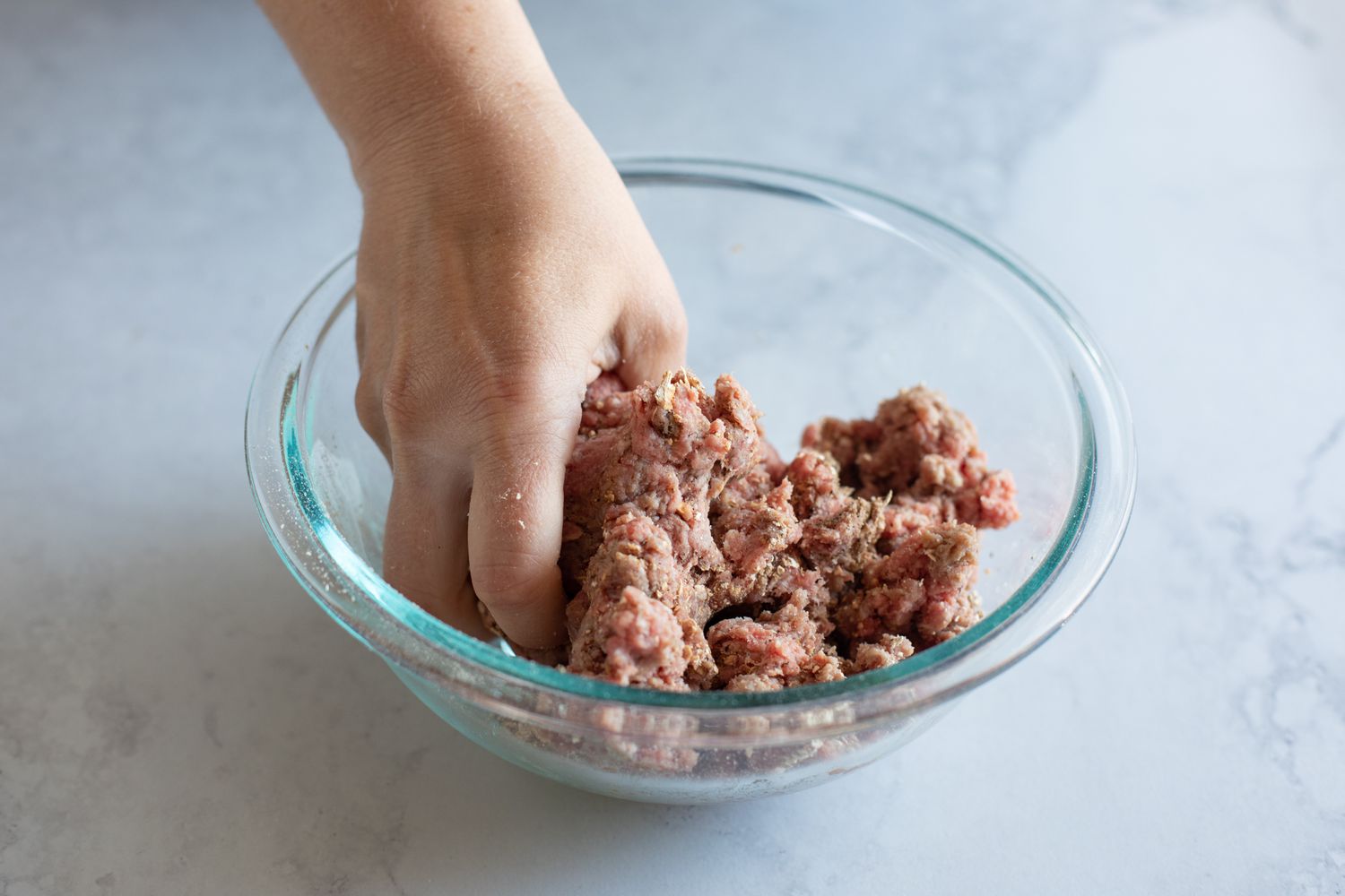 Mixing the spices into ground beef for a mushroom swiss burger recipe.