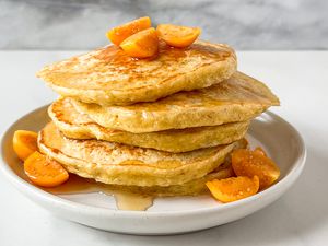 Stack of pancakes topped with sliced fruit