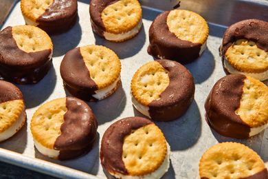 Ritz crackers assembled into ice cream sandwiches, partially dipped in chocolate, on a tray