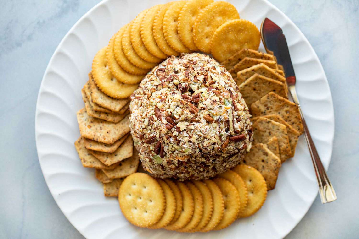 A plate of crackers with a cheese ball in the center, ready to serve and eat