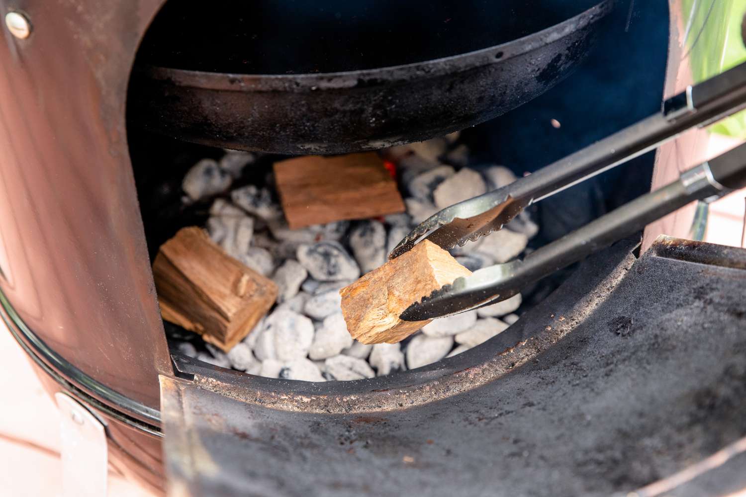 Adding wood chunks to a smoker to make a brined smoked turkey