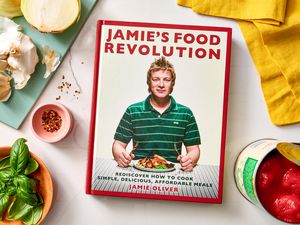 Jamie Olivers cookbook titled Jamies Food Revolution surrounded by cooking ingredients