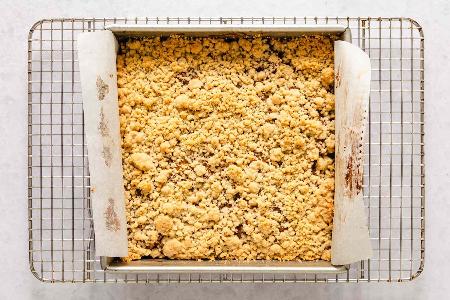 A pan of baked caramel apple bars with a crumble topping on a cooling rack