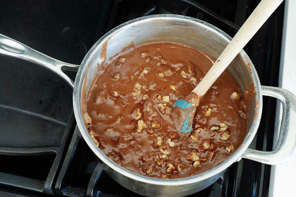 Homemade fudge in a saucepan with a spatula.
