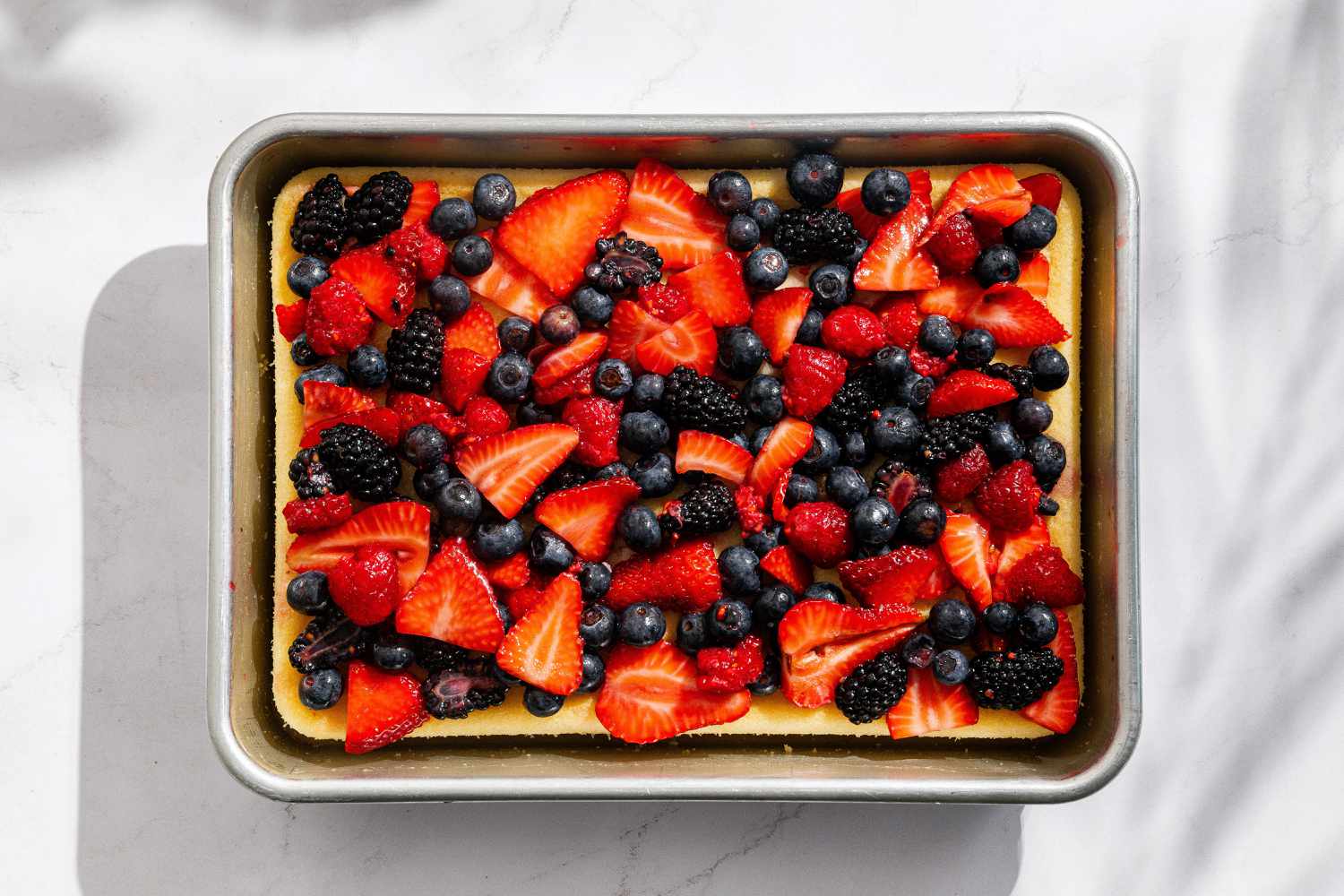 Overhead view of baked cake topped with fresh berries for Easy Berry Chantilly Cake