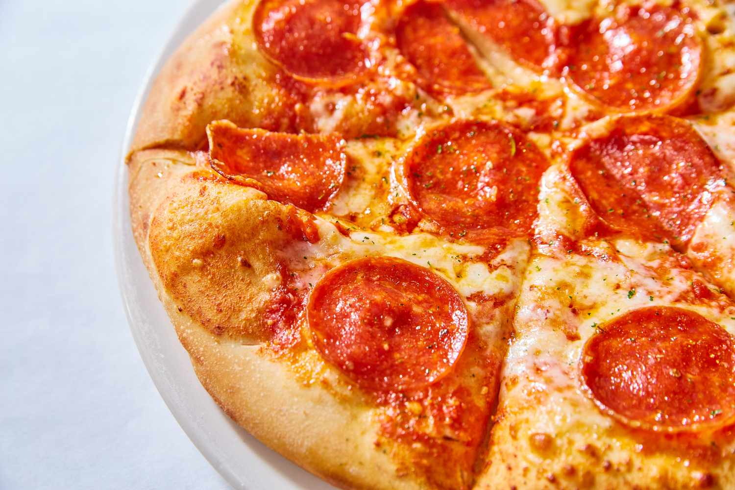 A closeup of a pepperoni pizza sliced into pieces on a plate