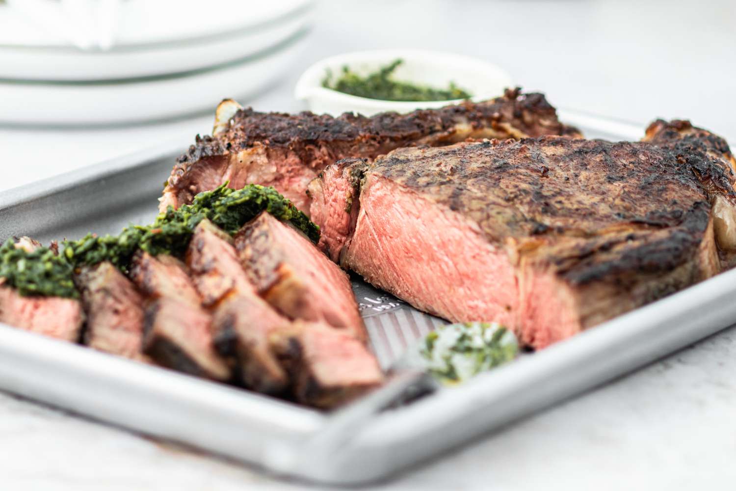 A cowboy ribeye steak sliced on a baking sheet