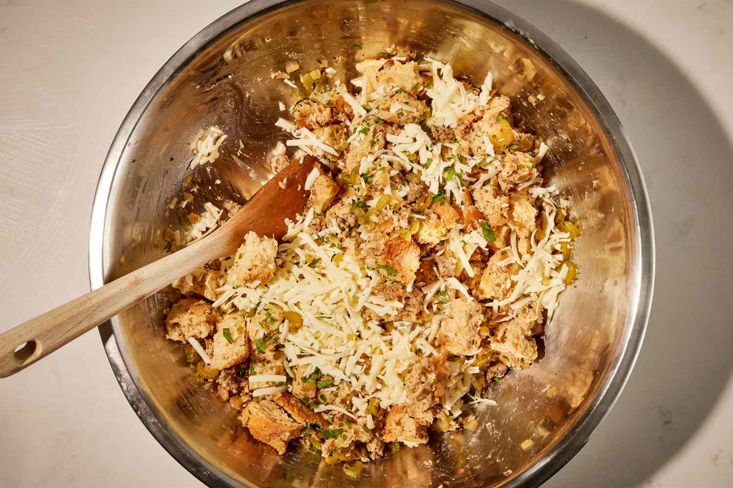 Overhead view of a saucepan with a wooden spoon after adding all the remaining ingredients for Wisconsin Stuffing recipe