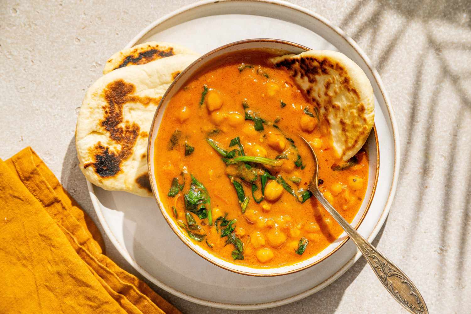 Easy Chickpea Curry in a bowl with a spoon, naan on the side