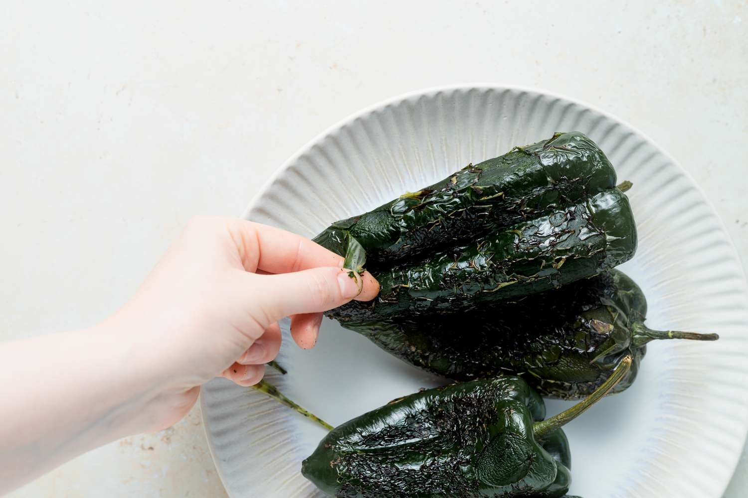 A hand holding part of a chili to make chili relleno casserole.