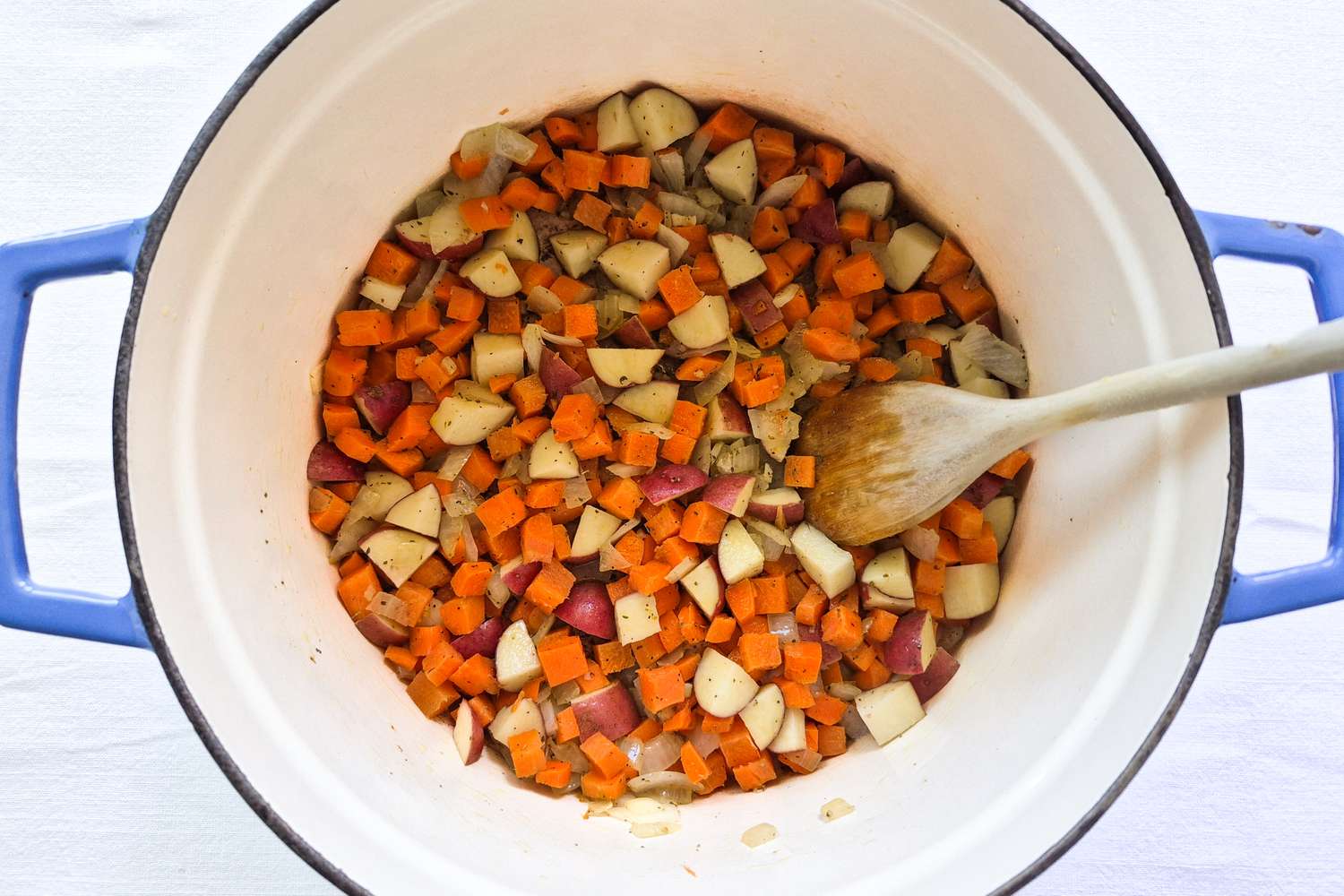 Diced vegetables in a pot with a wooden spoon