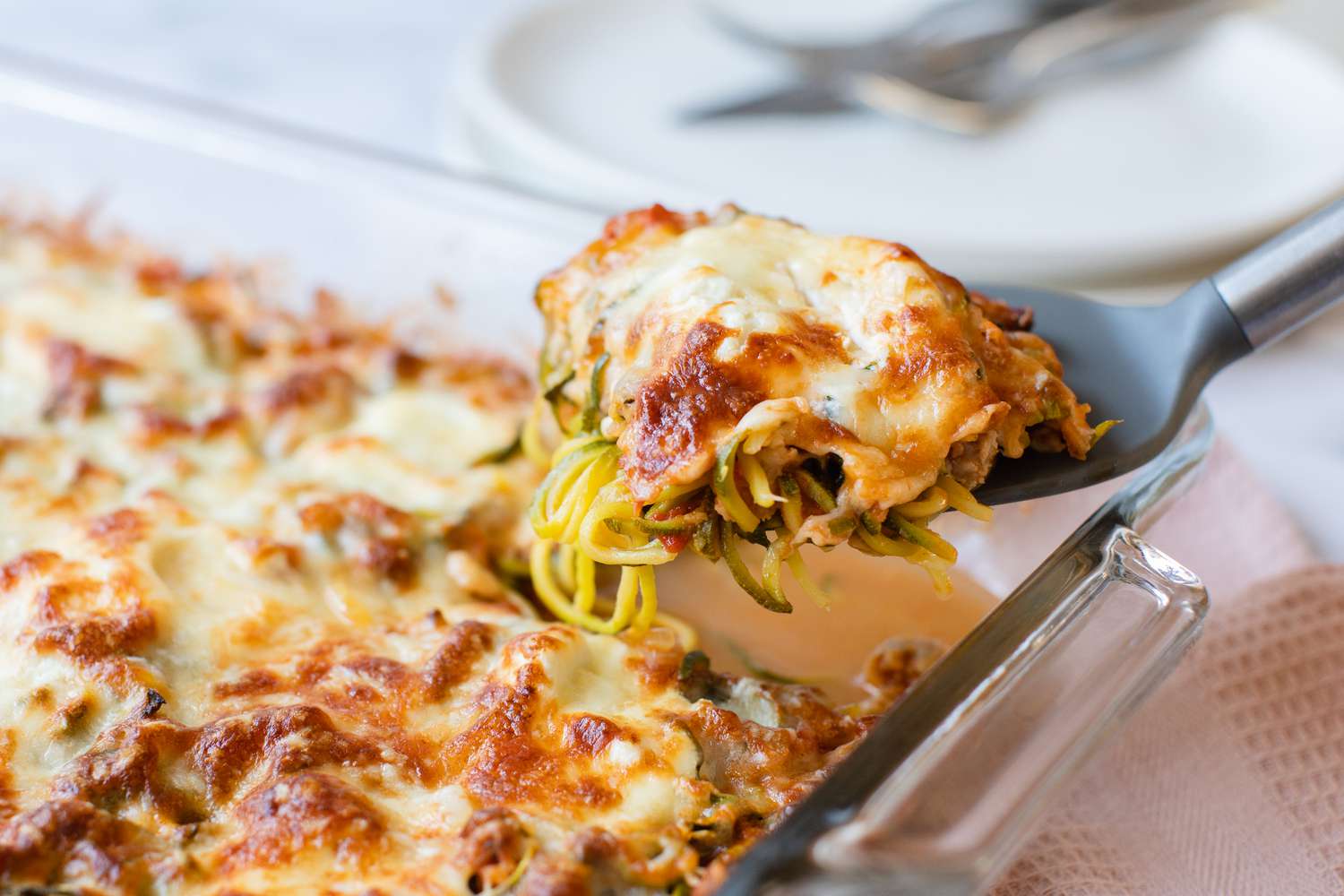 Zucchini Noodle Casserole in a Casserole Dish with Some on a Spatula
