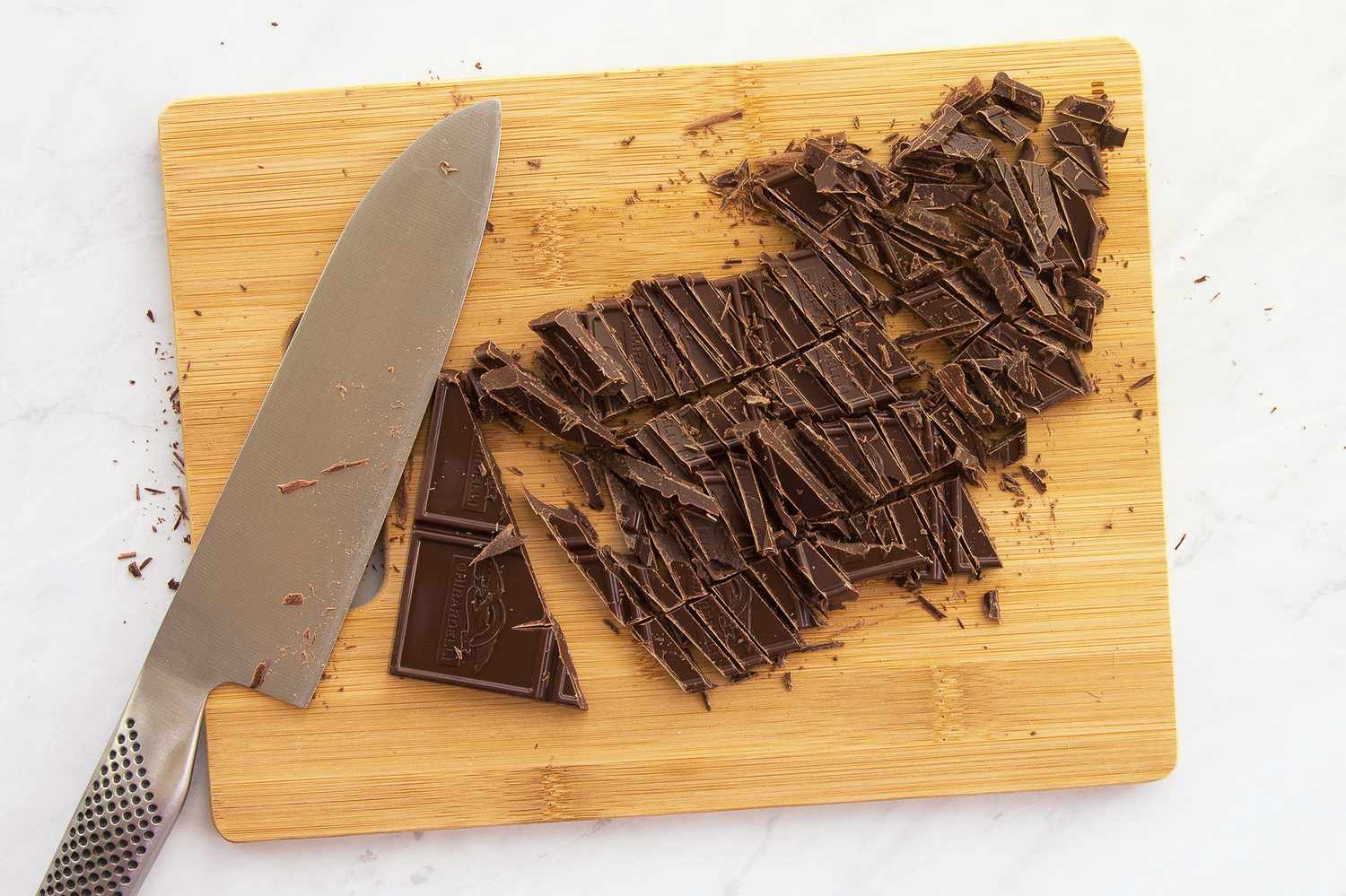 Chopped chocolate and a knife on a wooden cutting board