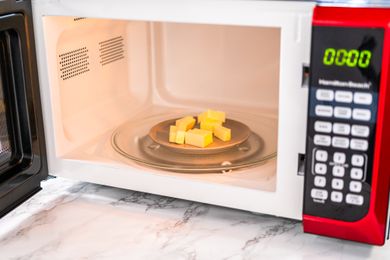 Butter cubes on a plate in a microwave oven with a marble countertop visible