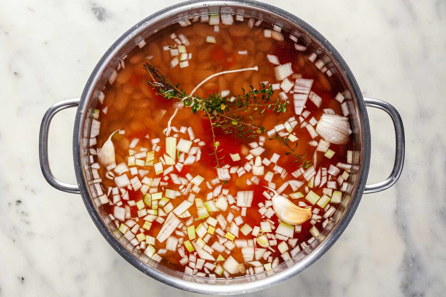 Beans, tomatoes, and aromatics in pot.
