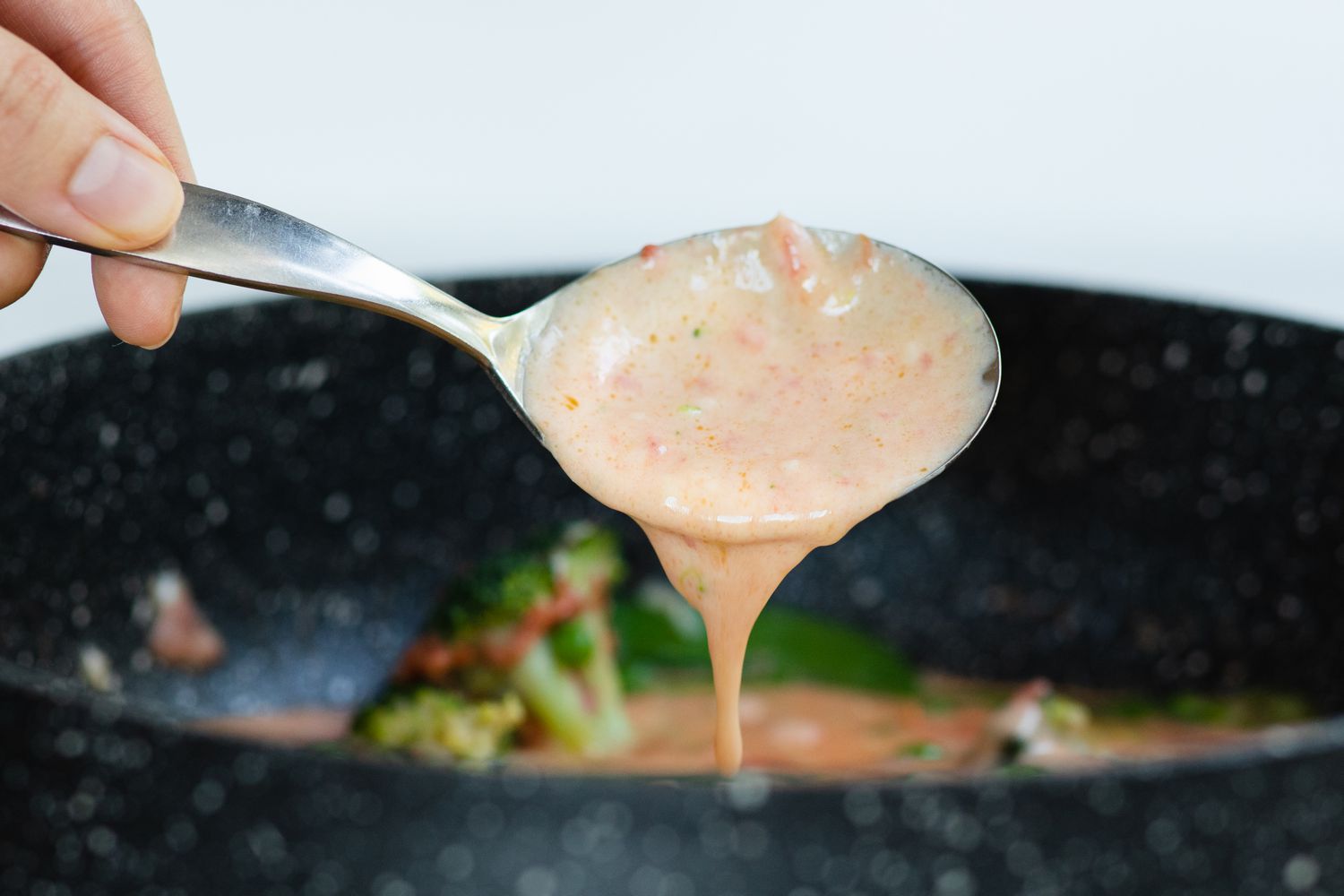 Spooning primavera sauce from the skillet.