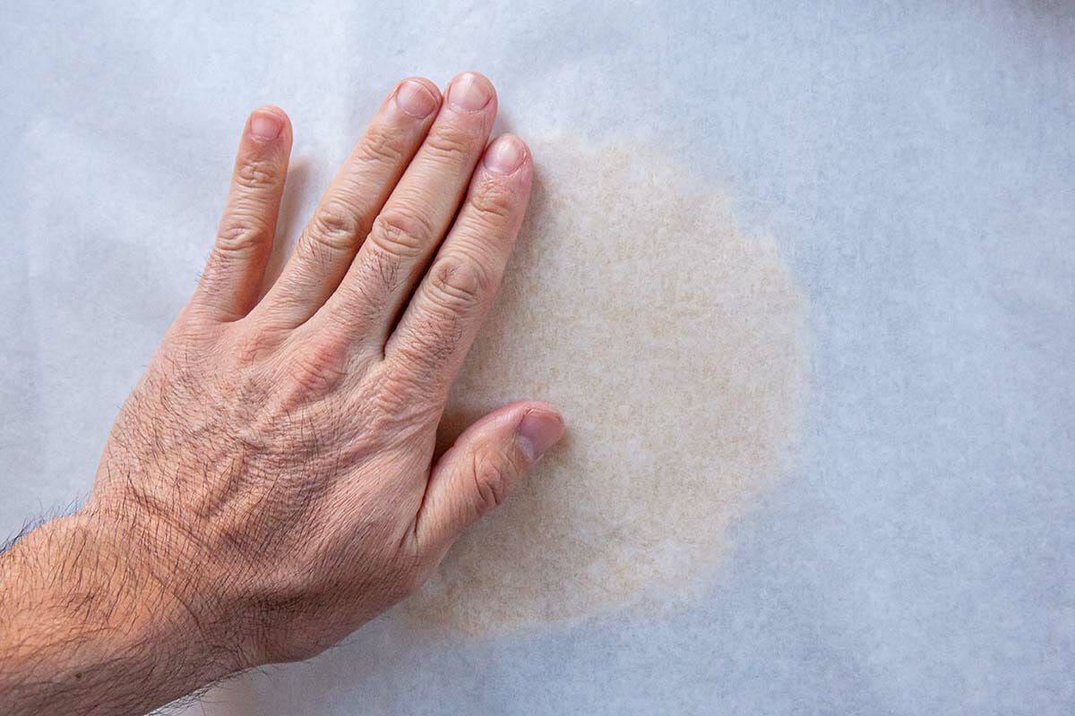Hand pressed dough circle of dough under parchment to make Easy Sugar Cookies.