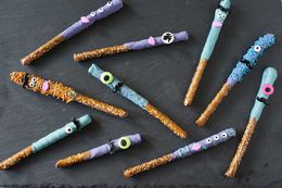 Homemade halloween-themed chocoalte covered pretzels on a dark gray background.