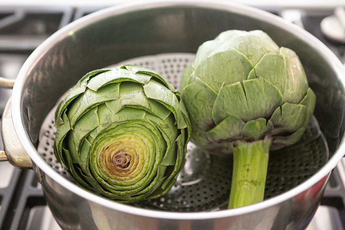 Two artichokes in a steamer basket in a pot