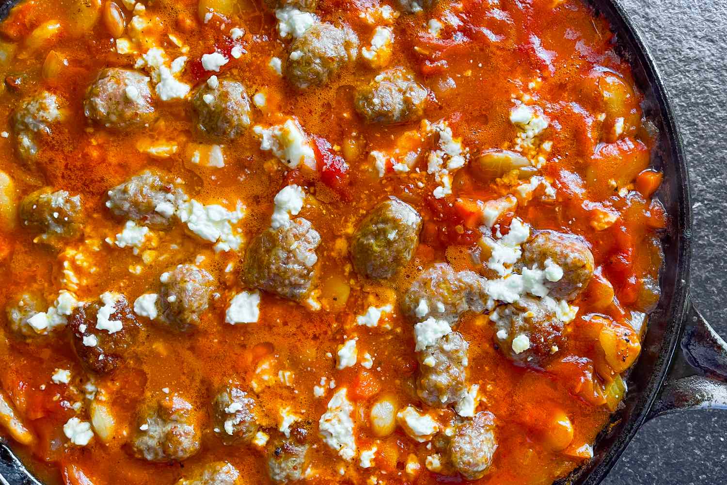 Vegetarian baked casserole topped with feta cheese and meatballs in a skillet