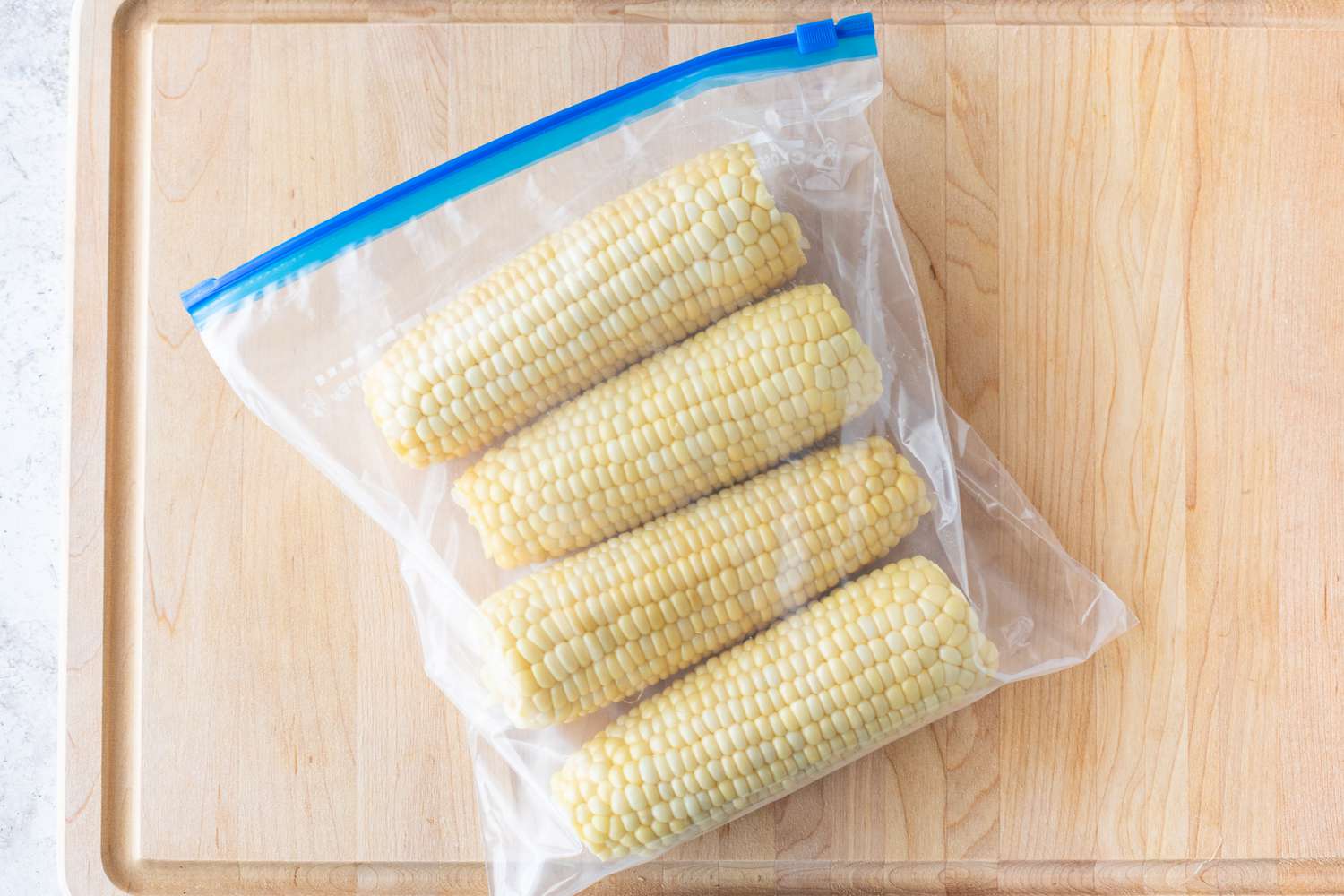 Corn cobs in a plastic bag on a wood cutting board