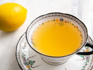 Teacup With Honey and Lemon Tea on a Saucer Next to a Lemon 