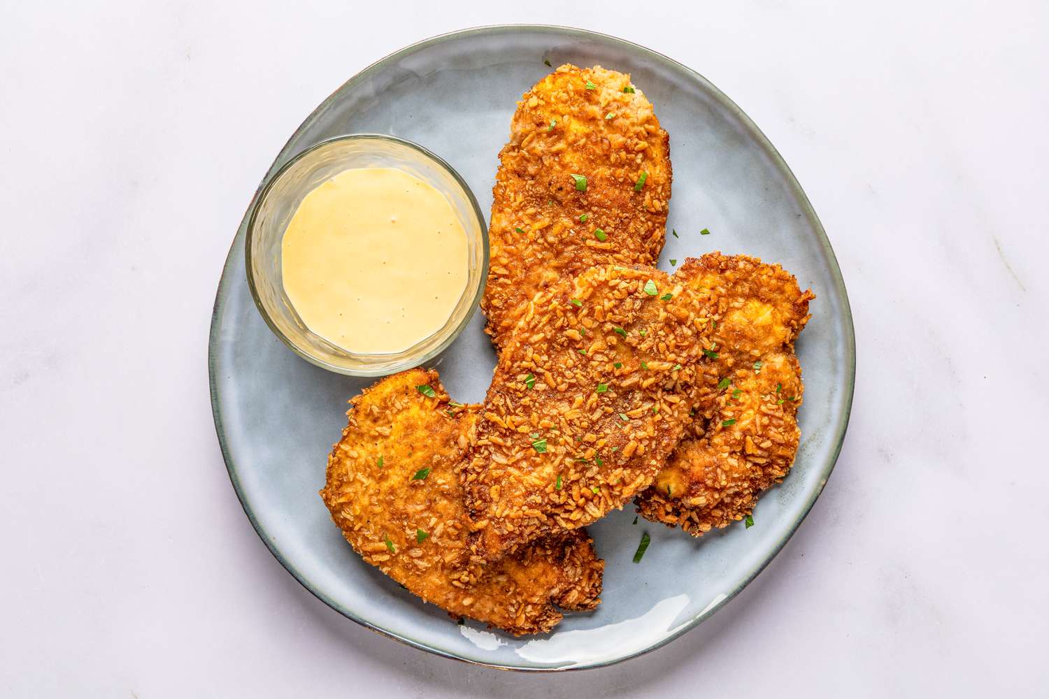 plate with pretzel chicken and a bowl of honey djion mayonnaise