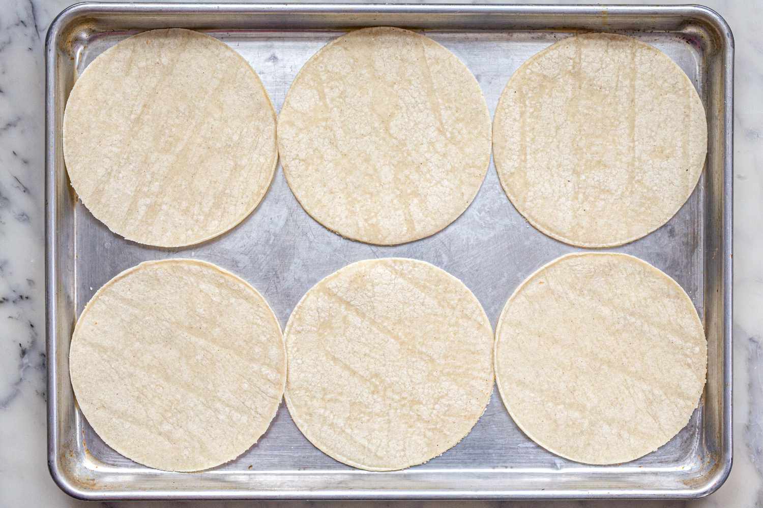 A sheet pan with six tortillas on it 