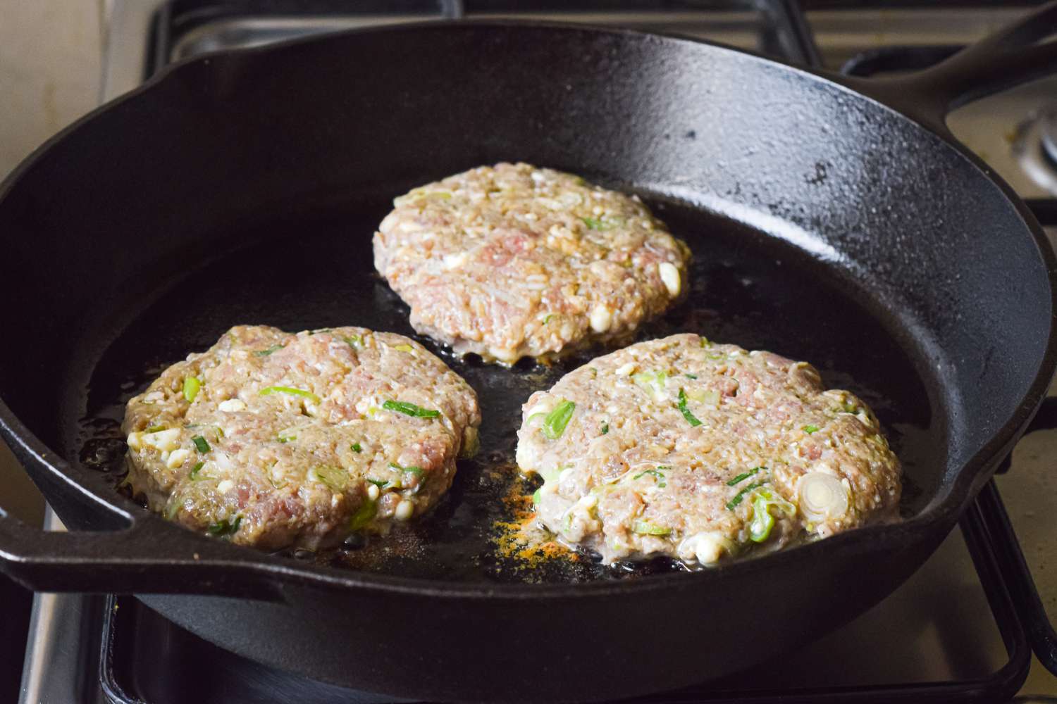 Blue Cheese Burger Patties Cooking in a Cast Iron Skillet 