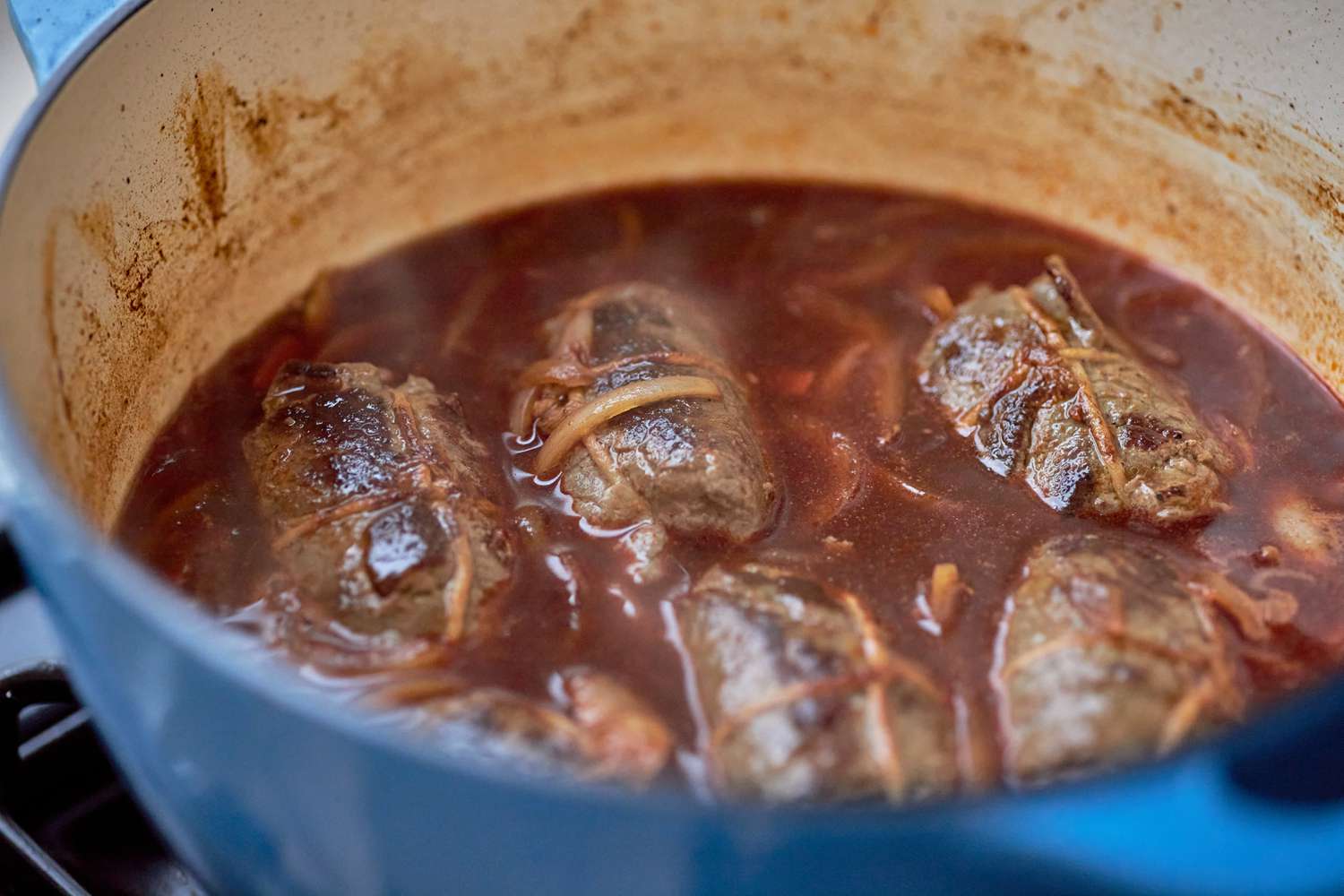 Rouladen added to the braising sauce in the Dutch oven