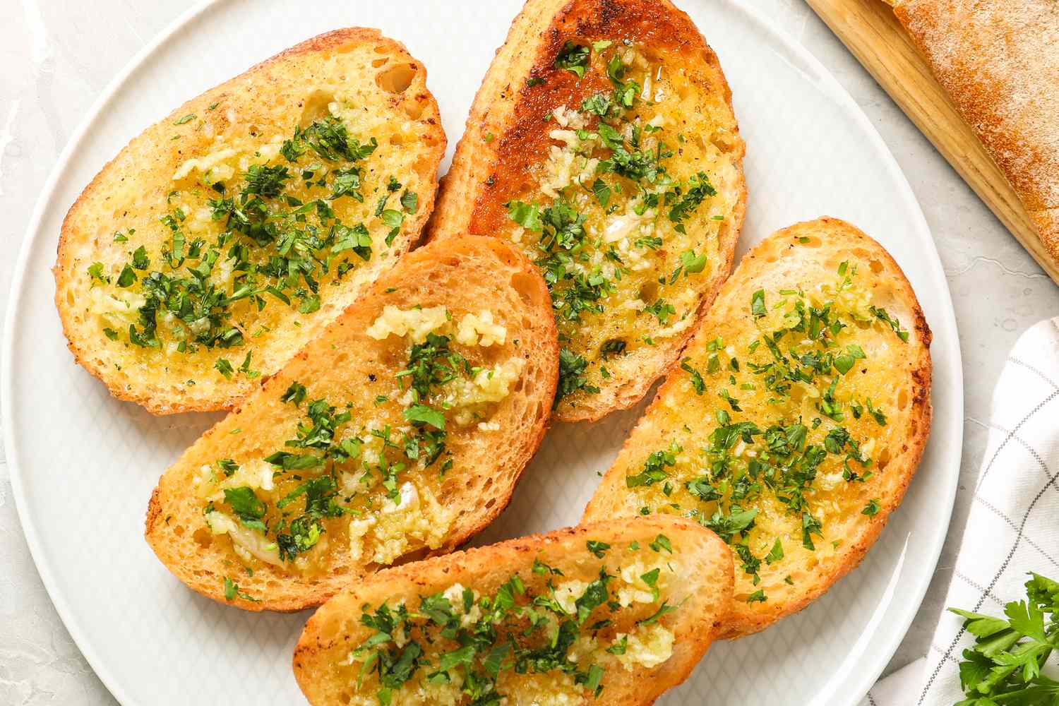 Slices of garlic bread garnished with herbs arranged on a plate