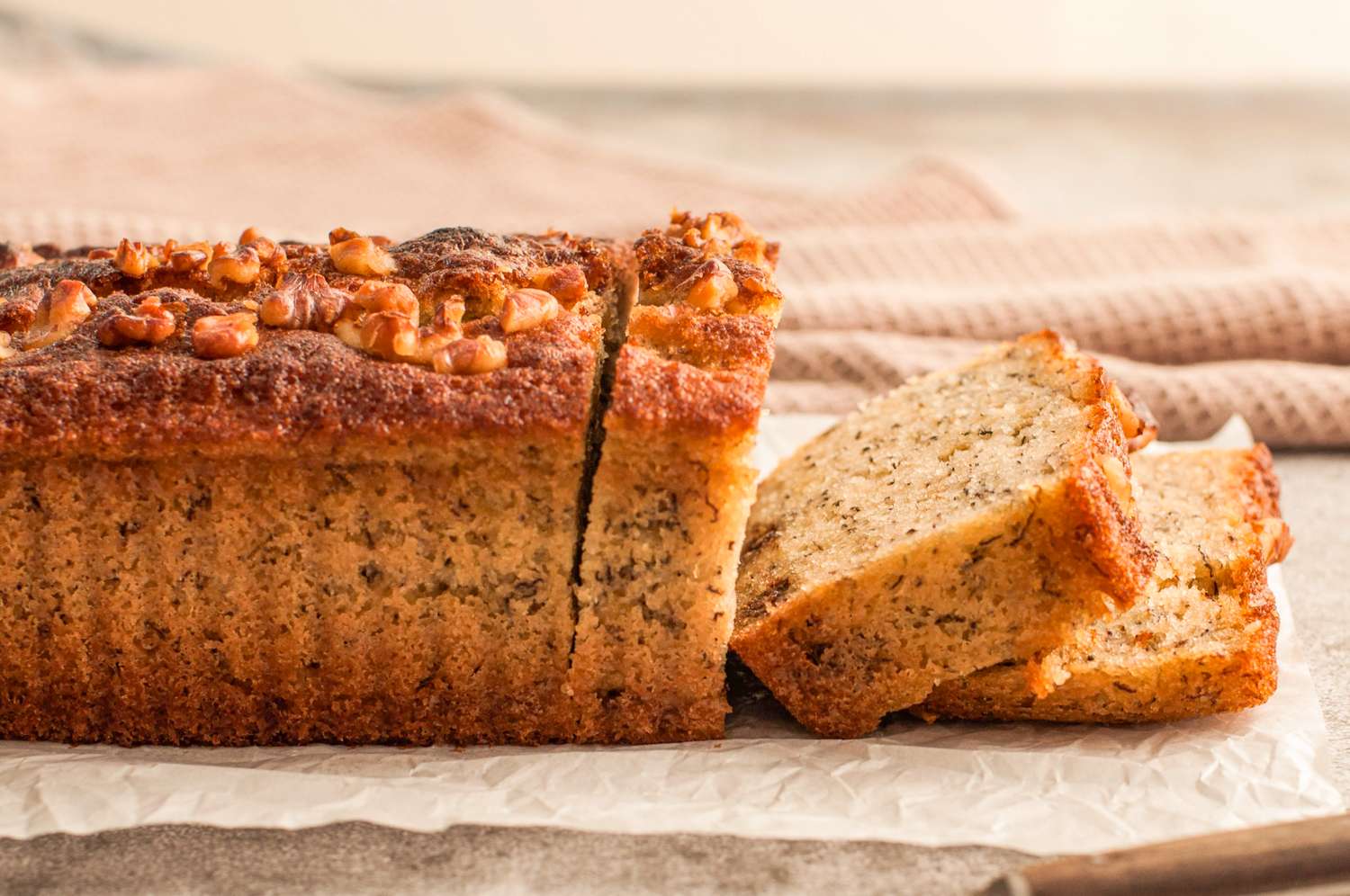A loaf of banana bread with a few slices cut displayed on a wooden surface
