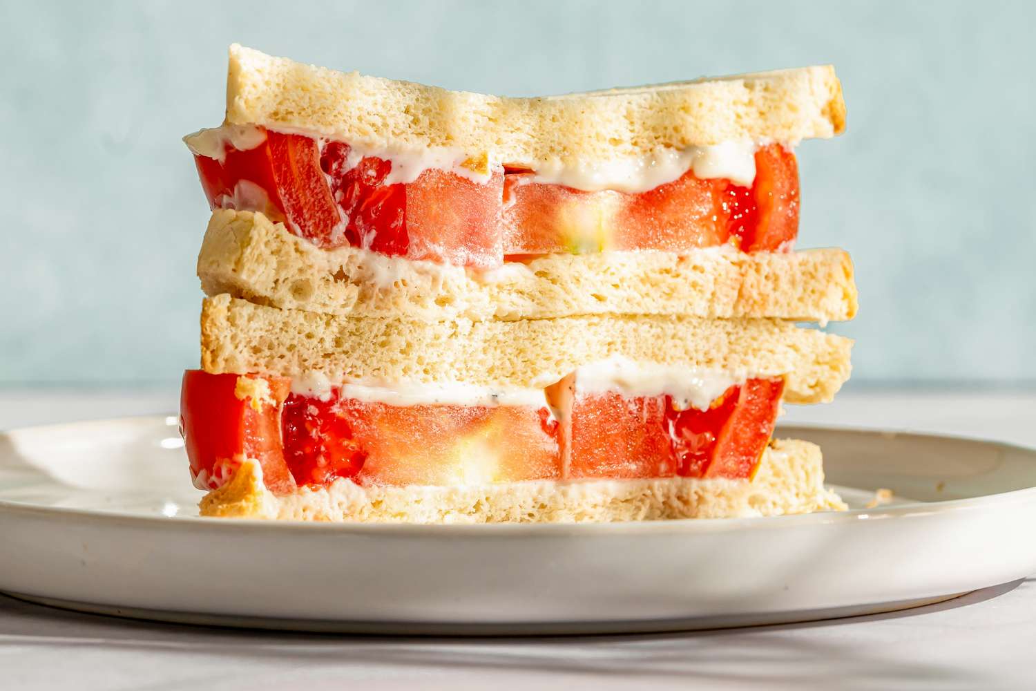 A tomato sandwich stacked, served on a plate