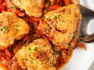 Roasted chicken thighs served atop a vibrant peperonata of sauted peppers and onions