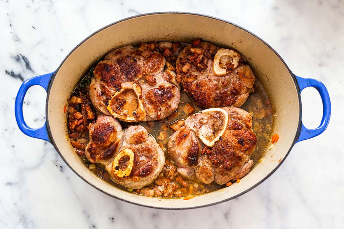 Ossobuco cooking in a blue dutch oven.