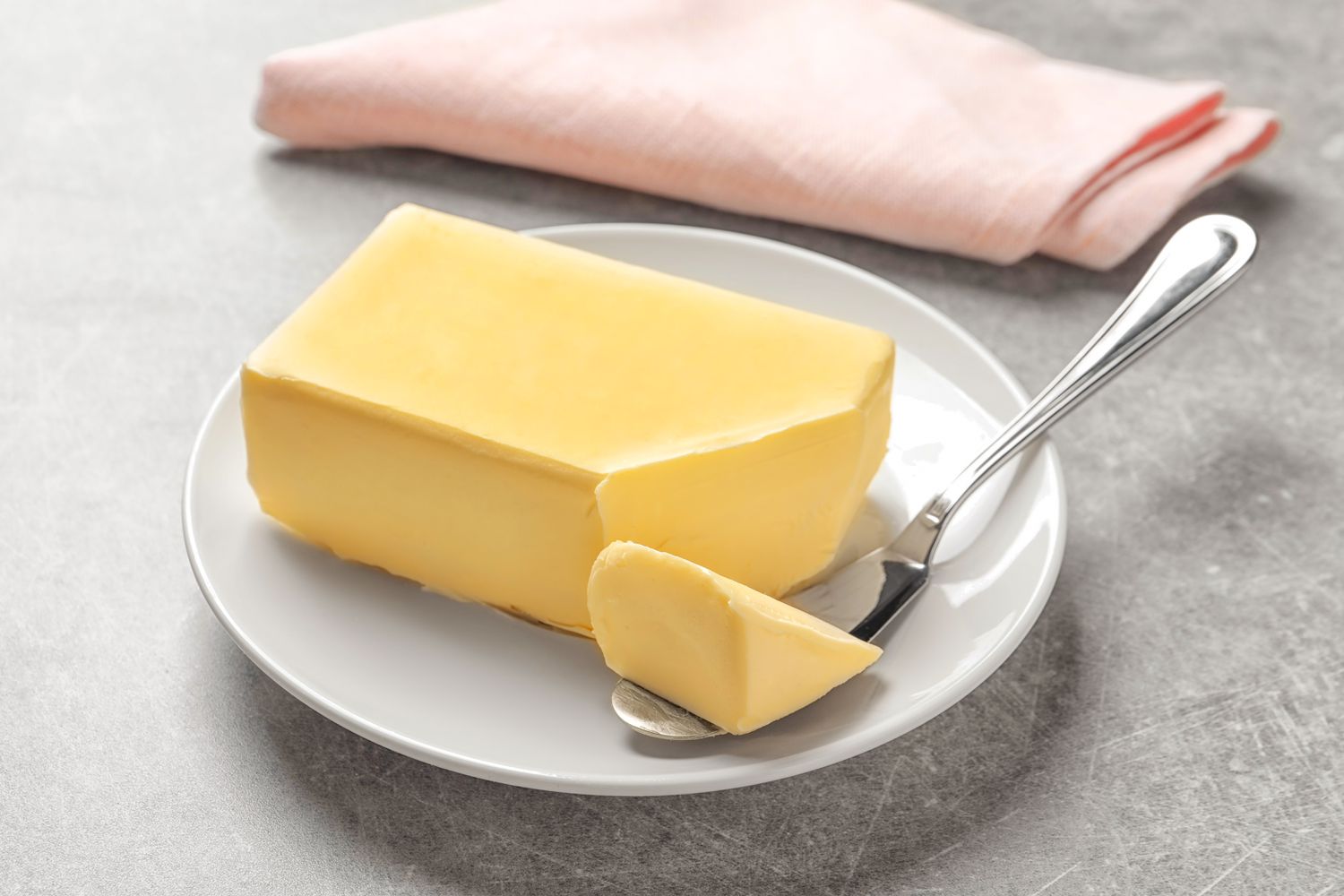 A block of butter on a plate with a butter knife