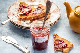 Strawberry Jam Surrounded by Toast on Plate, Utensils, and Tea Pot on Table