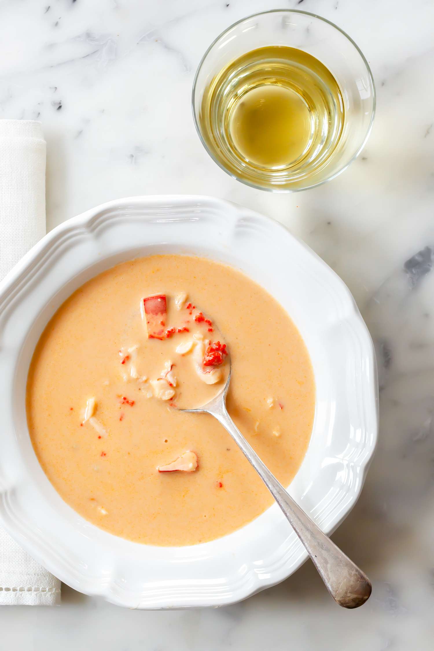 Bowl of Lobster Bisque with a Spoon Next to a Table Napkin and a Glass