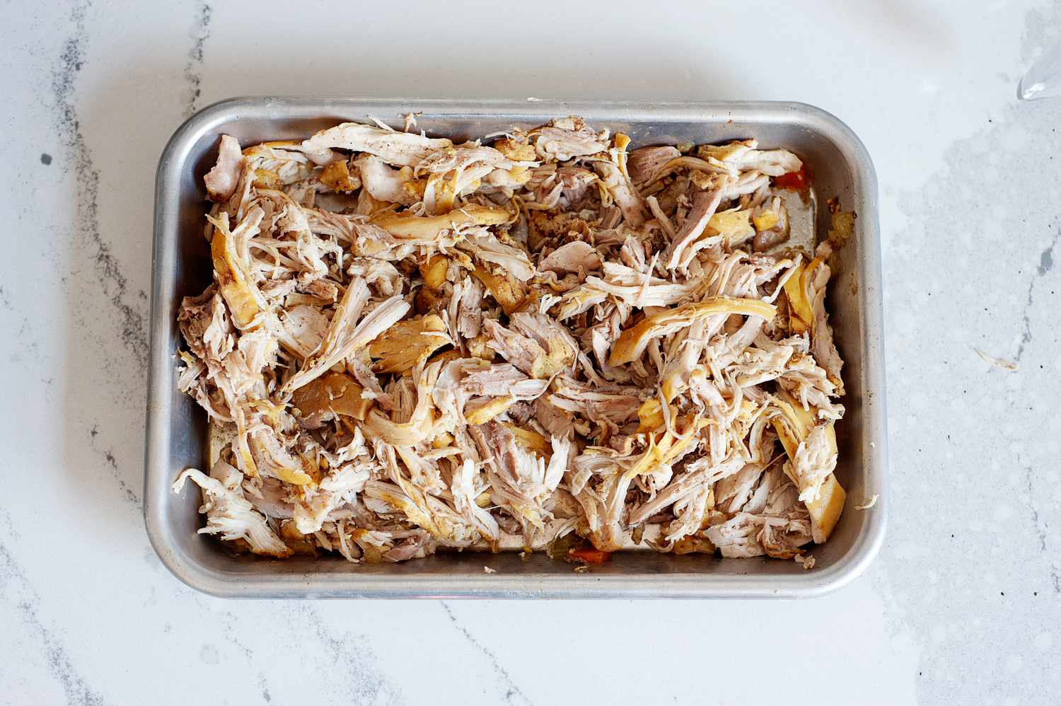 Shredded chicken in a baking dish to make “Ripe Figs” lemon chicken soup.