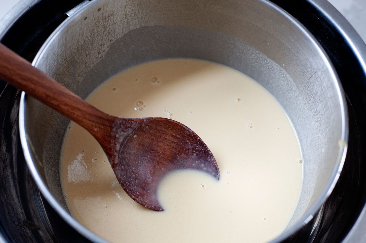 Adding custard to the heavy cream to make a butter pecan ice cream recipe.