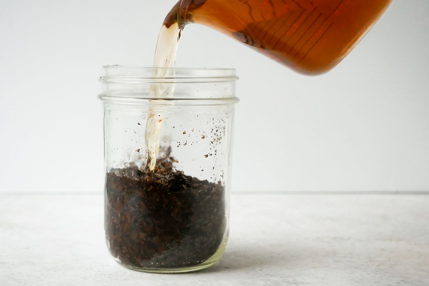 Pouring rum into a mason jar of coffee means to make Quick and Easy Vegan Coffee Liqueur.