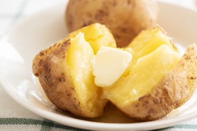 Closeup of split baked potatoes with butter in a white bowl