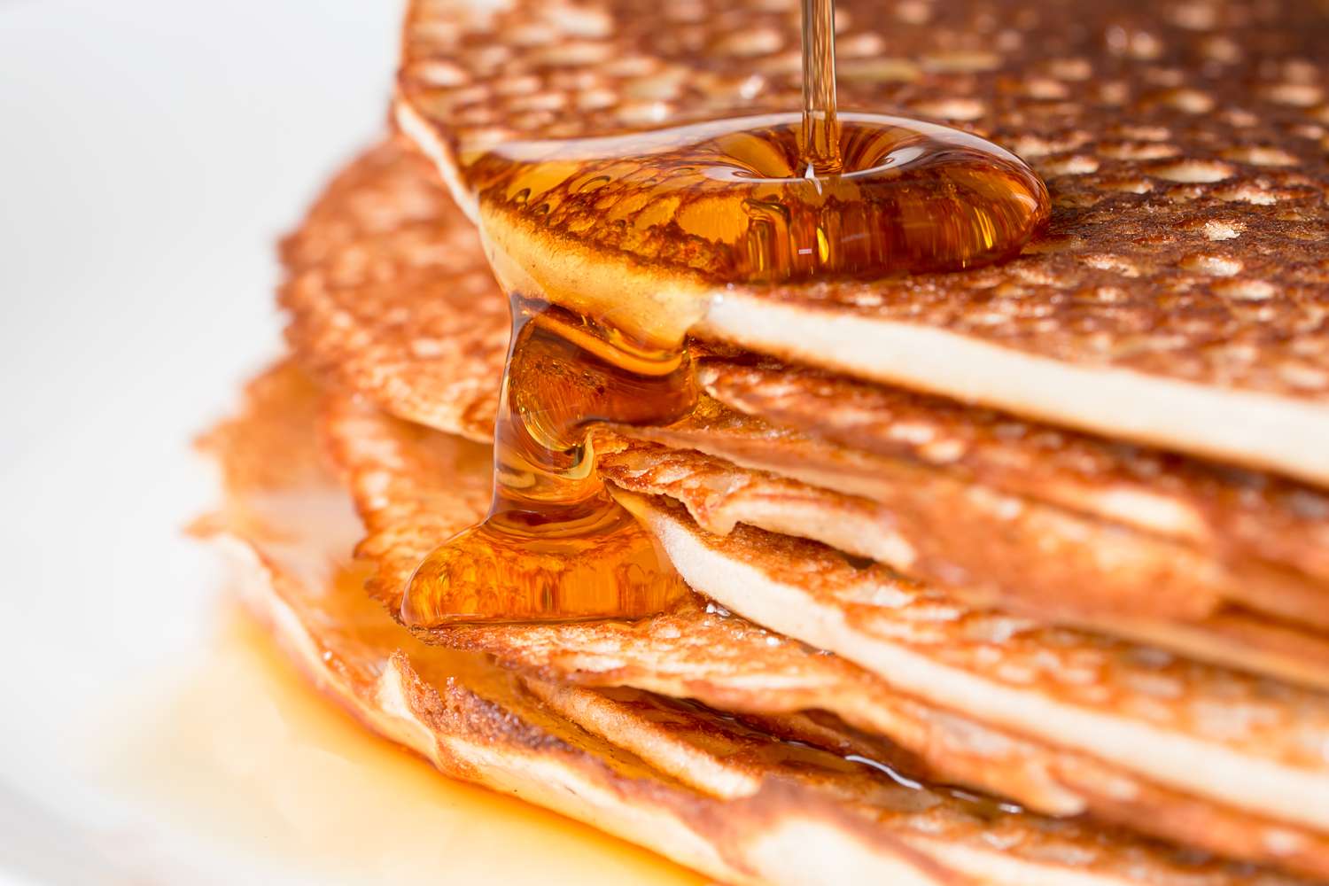 Stack of pancakes with syrup being poured over them