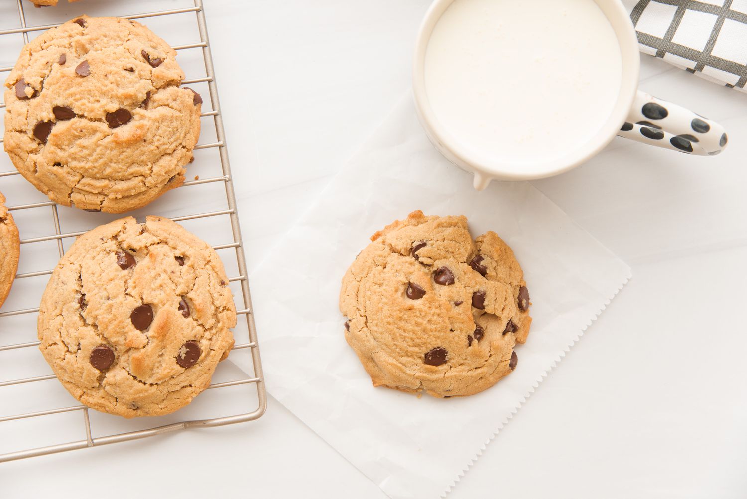 Overhead view of a glass of milk and Homemade Peanut Butter Chocolate Chip Cookies cooling on a rack.