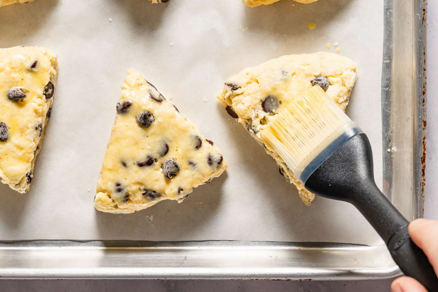 Scones being brushed with a glaze before baking for Chocolate Chip Scones recipe