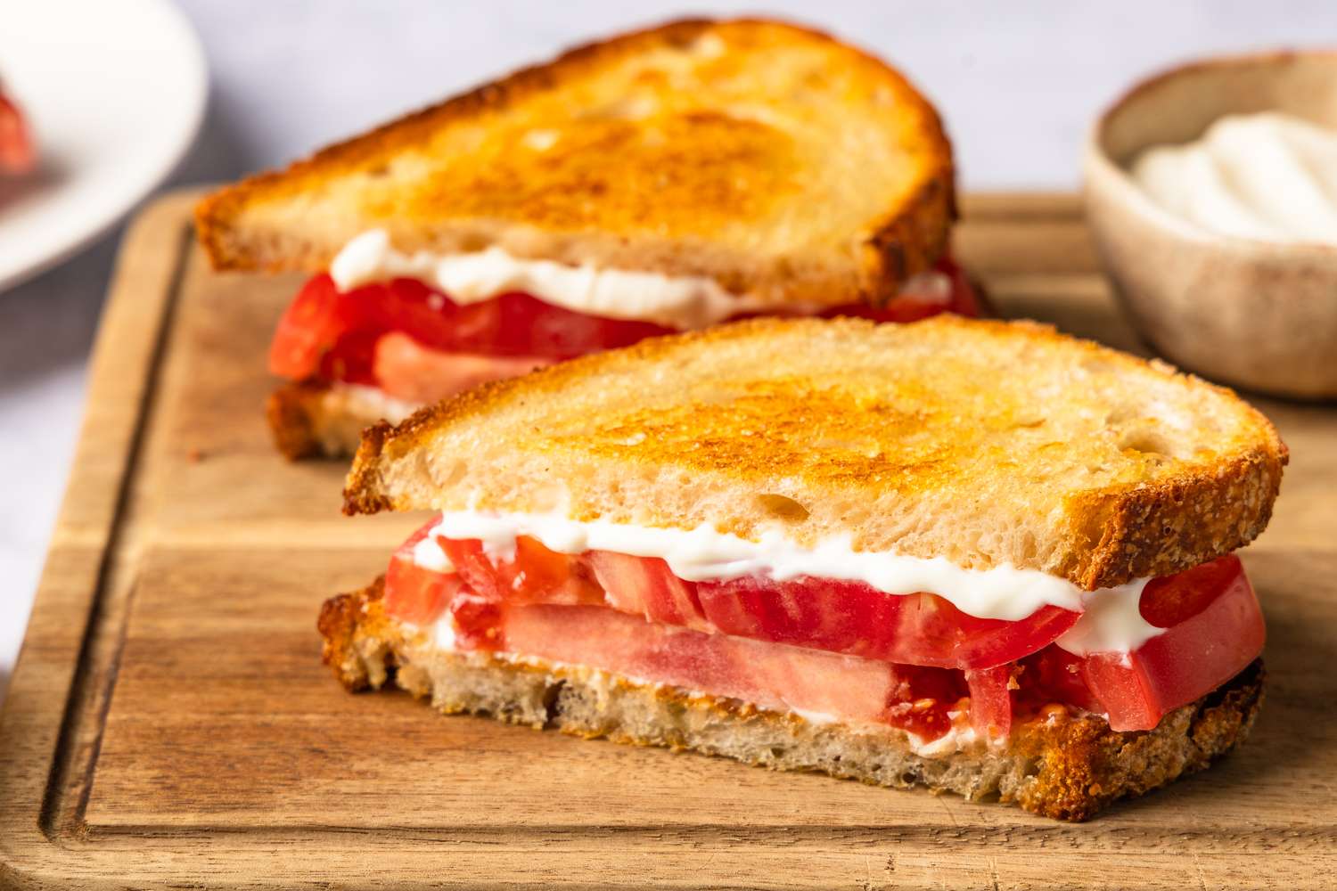 A sandwich with sliced tomatoes and mayonnaise on toasted bread